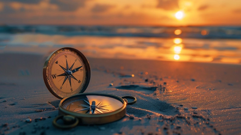 An open brass compass resting on a sandy beach at sunset, unattended, symbolizing moral direction that exists but goes unused.